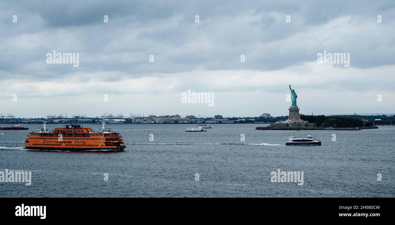 Le ferry de Staten Island navigue par Lady Liberty par une journée nuageux. Banque D'Images