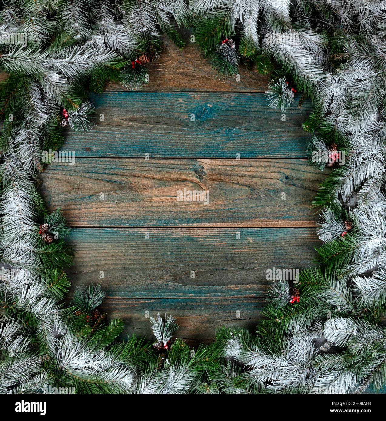 Vue en hauteur d'une couronne couverte de neige avec de petits cônes de pin dans la bordure circulaire sur des planches de bois vieillies bleues pour les vacances d'hiver de Noël ou Banque D'Images