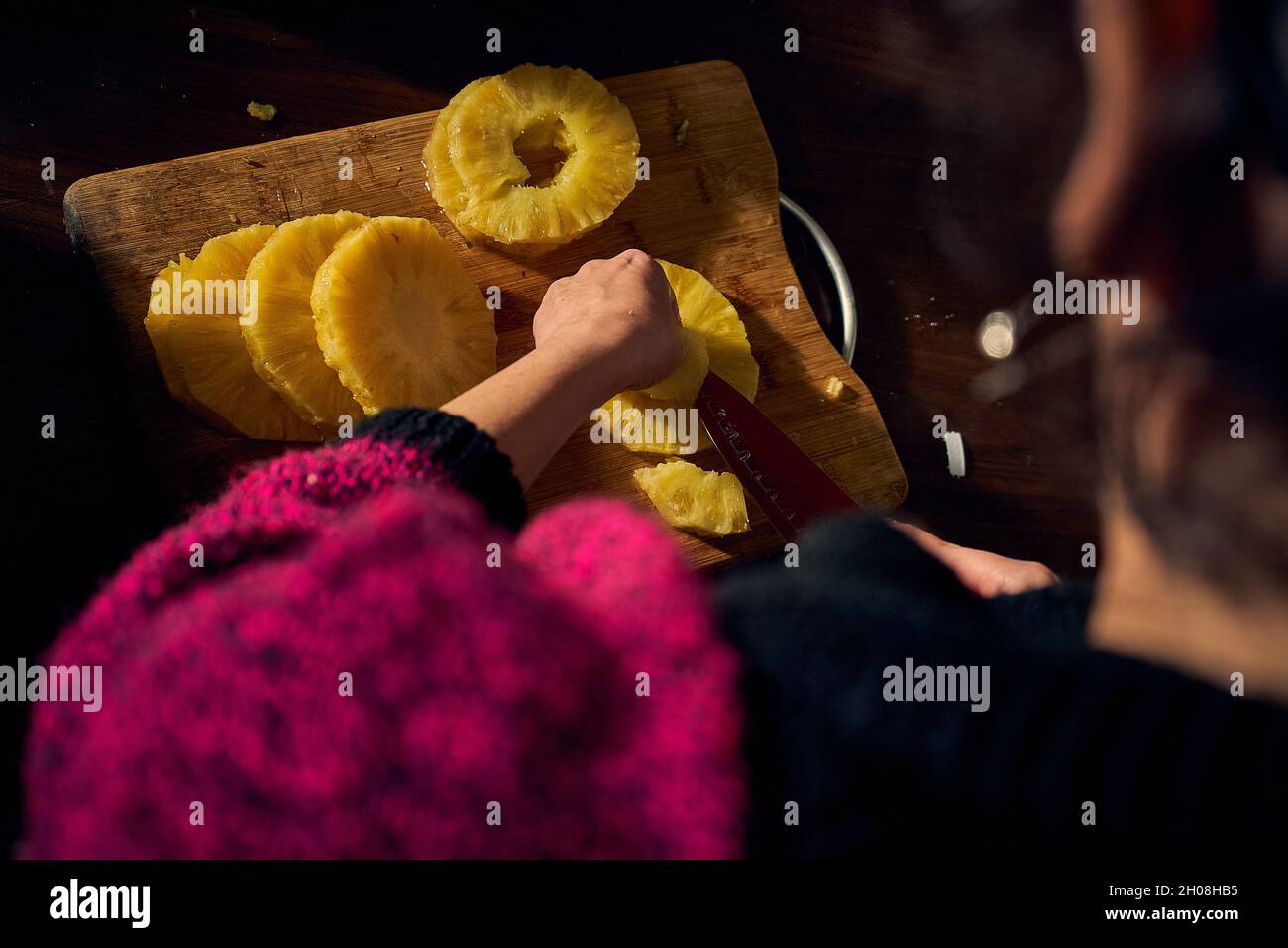 Une femme coupe des tranches d'ananas au coucher du soleil Banque D'Images