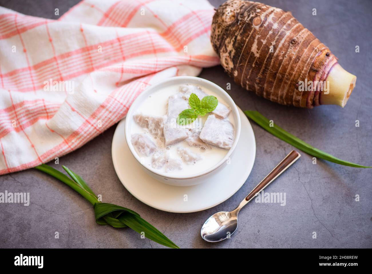 Taro alimentaire avec dessert taro bouilli avec du sucre et du lait de coco sur un bol et de la racine de taro frais cru bio prêt à cuire, cuisine thaïlandaise asiatique Banque D'Images