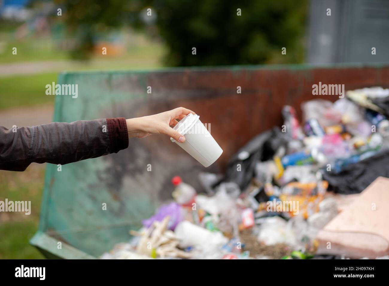 Femme jetant un verre de carton dans un bac de recyclage.Prendre soin de la propreté de la ville et de l'environnement.Une grande poubelle dans un Banque D'Images