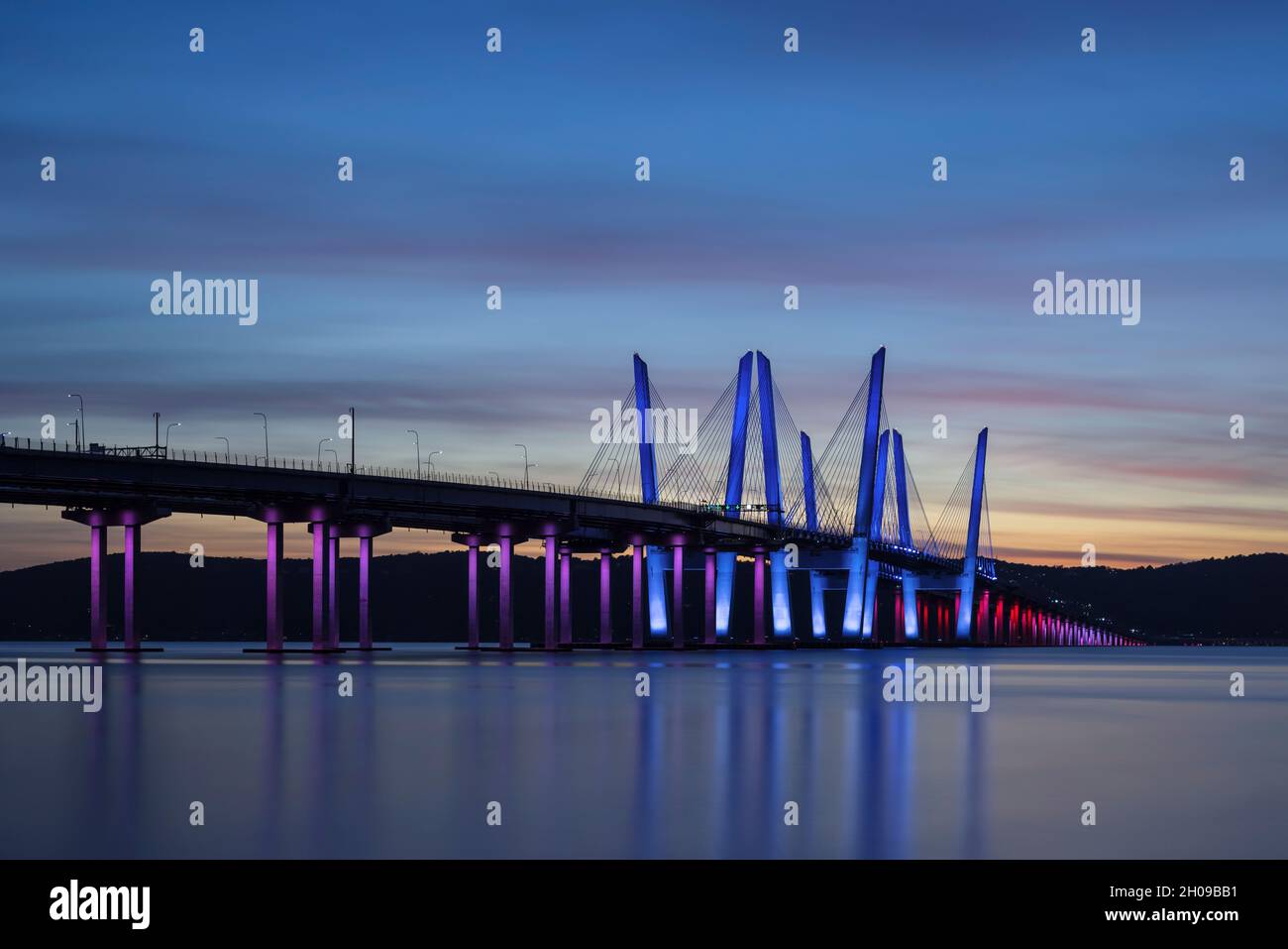 Le pont du gouverneur Mario M. Cuomo, illuminé en rouge, blanc et bleu en reconnaissance du jour de Columbus, traverse la rivière Hudson juste après le coucher du soleil. Banque D'Images