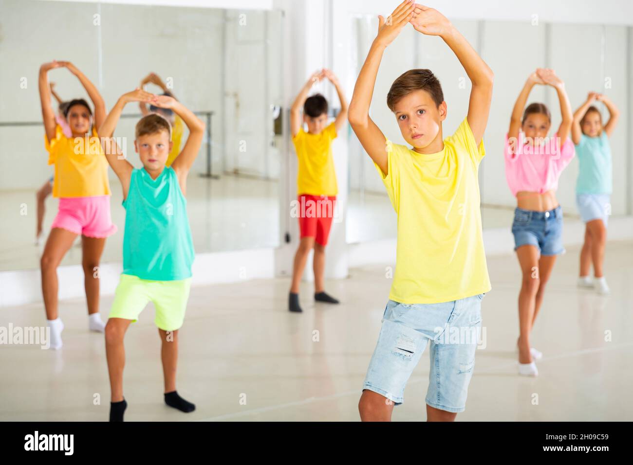 Tween garçon pratiquant des mouvements de flamenco pendant un cours de groupe en studio de chorégraphie Banque D'Images