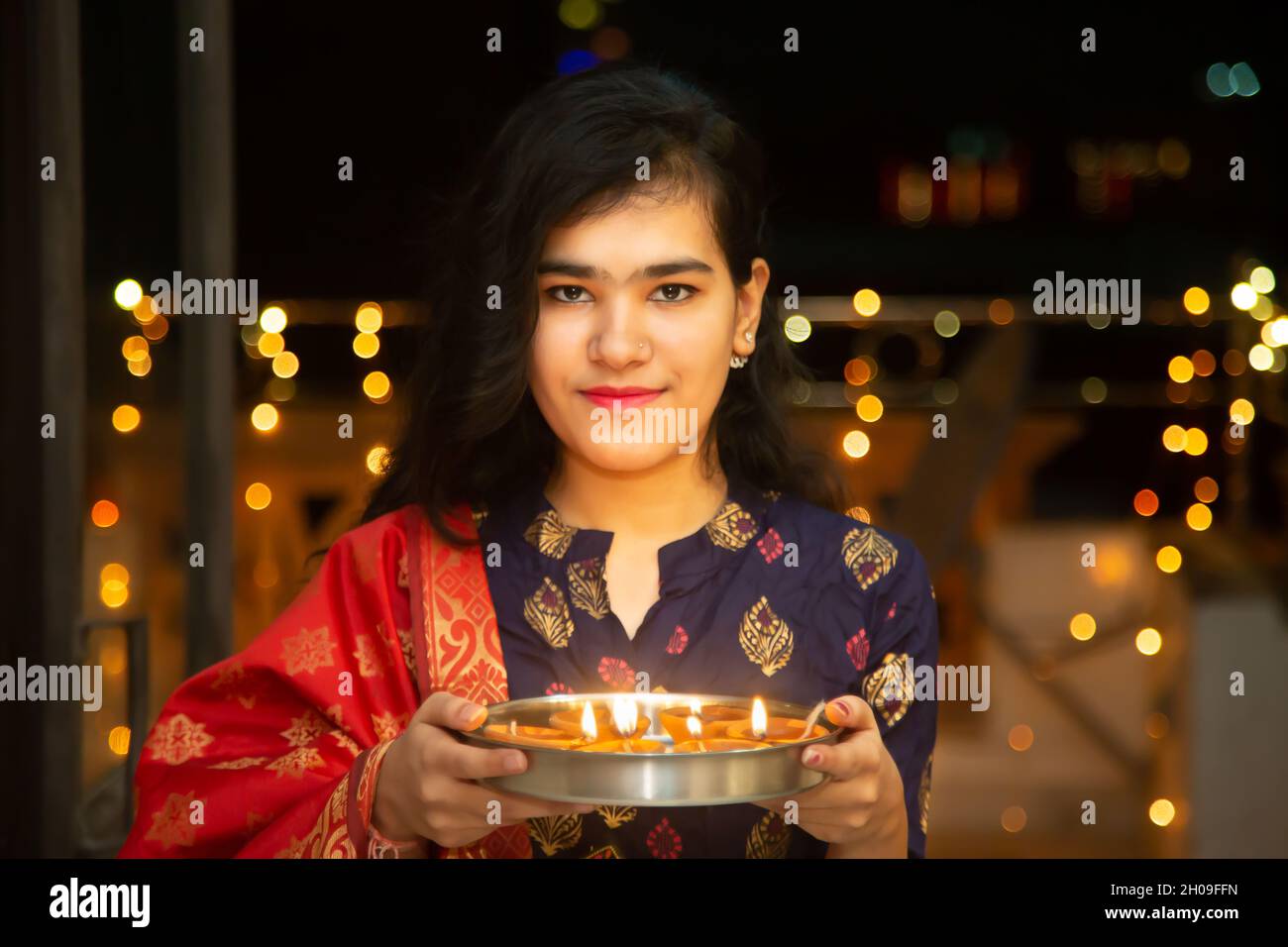 Portrait de Happy Young indian magnifique femme tenir plaque/thali avec diya/argile lampes à l'huile portant la robe traditionnelle, célèbre diwali, festival de lumières Banque D'Images