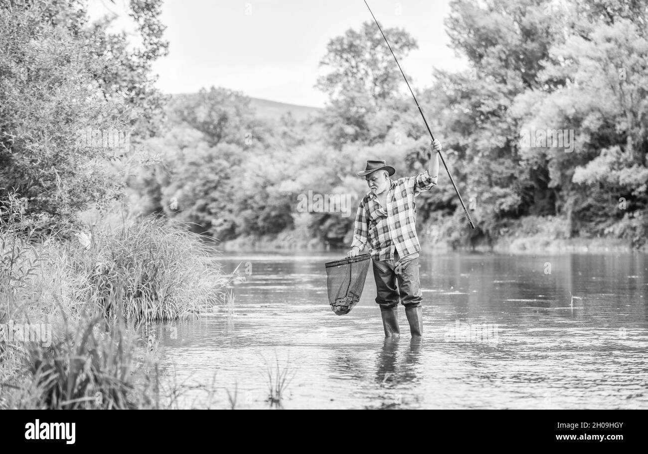 Des gens cool font de la pêche. Week-end d'été.Pêche au gros gibier. Homme mature pêche à la mouche. Homme attrapant du poisson. Pêcheur barbu à la retraite.Appât de truite. Pêcheur Banque D'Images