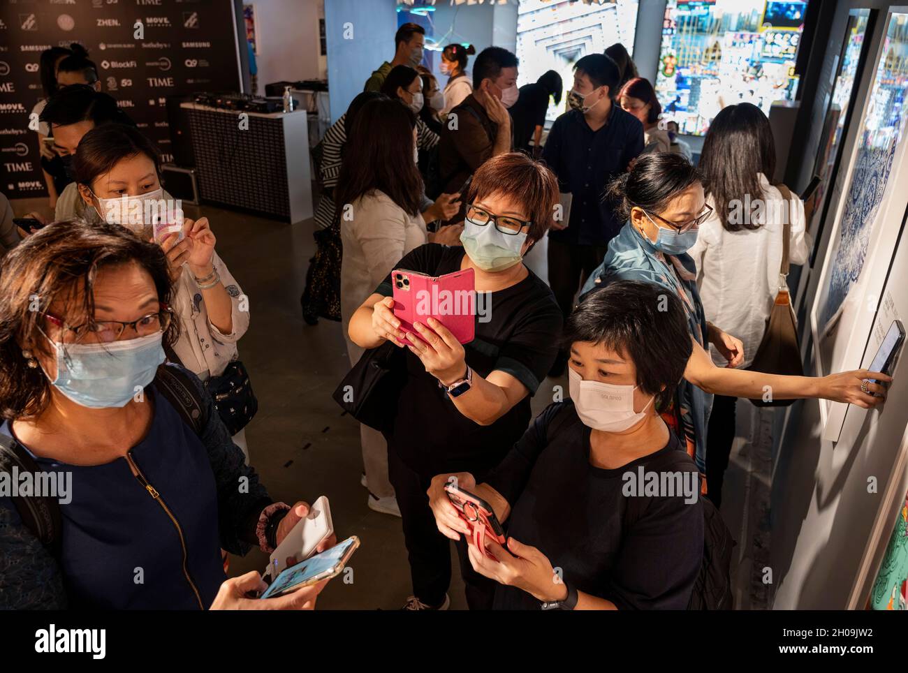 Les visiteurs numérisent et utilisent la réalité augmentée (AR) avec leurs smartphones pour interagir avec différentes œuvres d'art à la Foire d'art numérique Asie à Hong Kong, en Chine, le 08 octobre 2021.La foire présente NFT Crypto Art, jetons non fongibles, dans le cadre de la nouvelle tendance de l'art moderne Banque D'Images