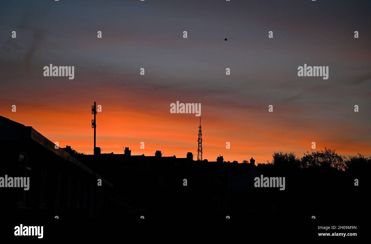 Brighton UK 12 octobre 2021 - Un beau lever de soleil sur les toits de Brighton et la station de transmission de Whitehawk Hill comme le temps sec chaud continue dans le Sud-est : Credit Simon Dack / Alamy Live News Banque D'Images