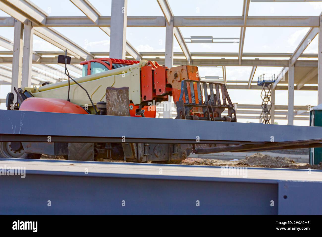 Chariot élévateur télescopique qui jusqu'à ce qu'il transporte une pile de poutres métalliques peintes et soudées, poutres de structure pour la construction métallique sur le chantier de construction. Banque D'Images