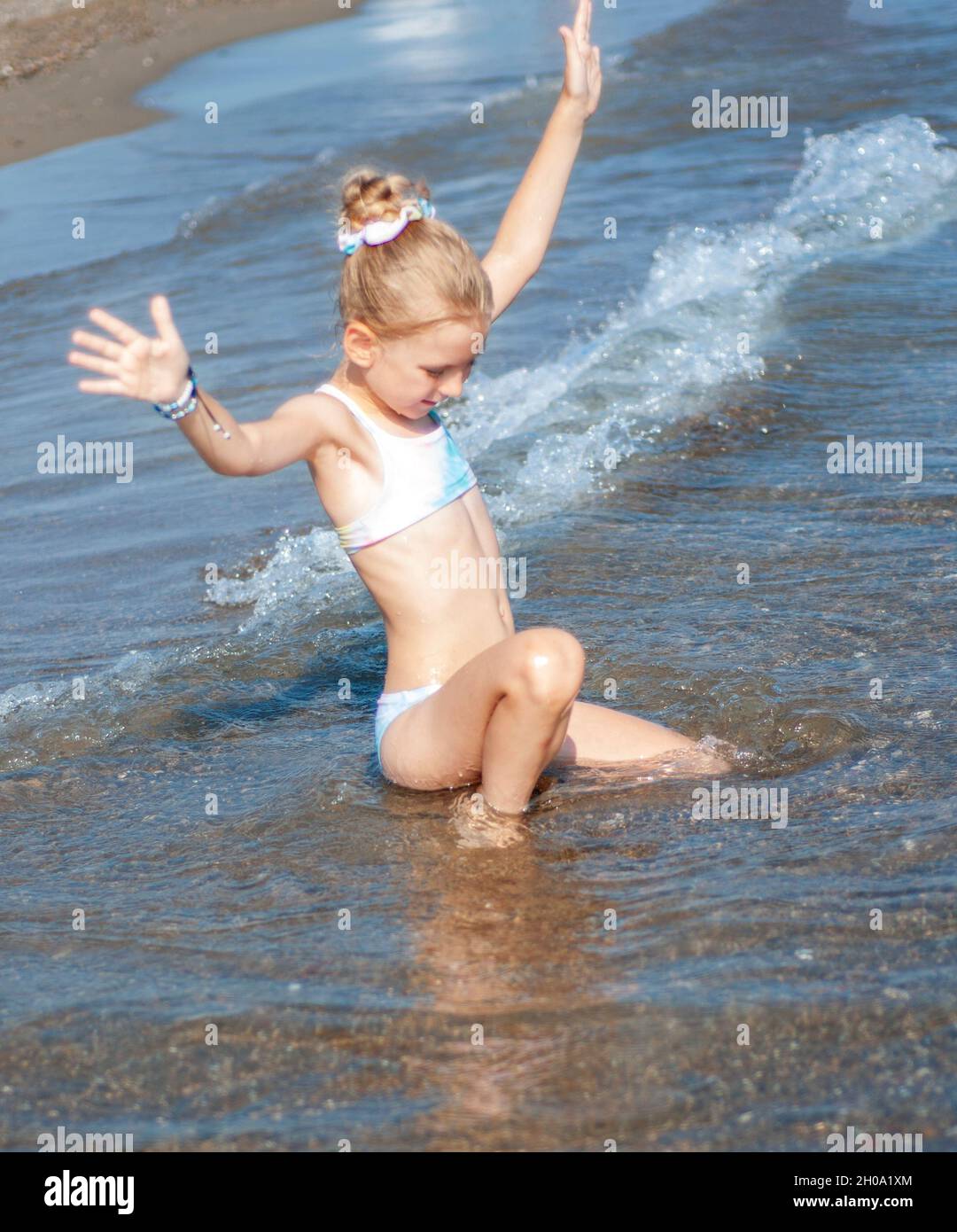 Petite fille dans un maillot de bain jouant sur la plage au bord de la mer  Photo Stock - Alamy