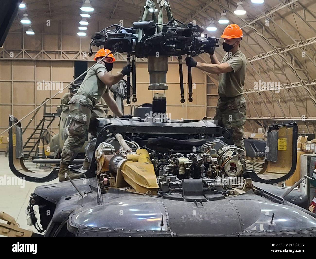 Les soldats américains de la Bravo Company, 628e Bataillon de soutien de l’aviation, 28e Brigade de l’aviation de combat expéditionnaire réinstallèrent la tête du rotor principal sur un hélicoptère UH-60 Black Hawk après l’entretien de routine d’un aérodrome de la 28e zone d’opérations de la CEAB au Moyen-Orient. Banque D'Images