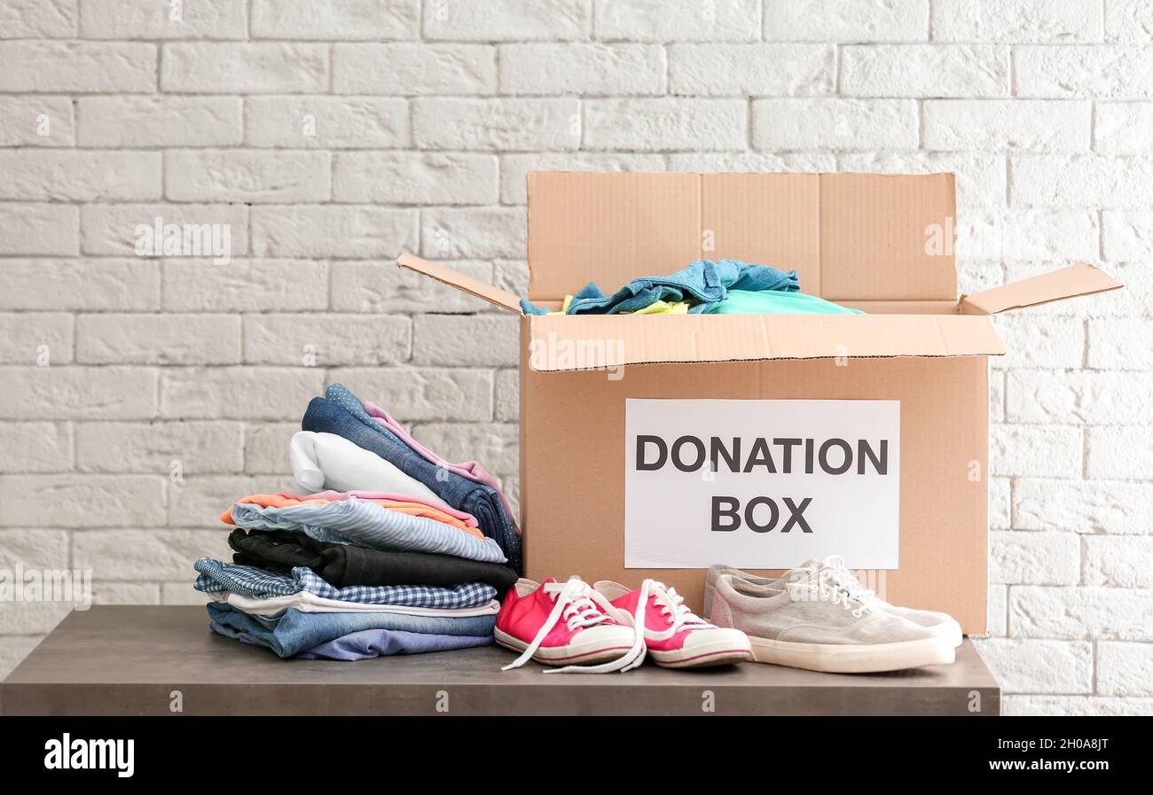 Boîte à dons avec vêtements et chaussures sur la table contre le mur de  briques Photo Stock - Alamy