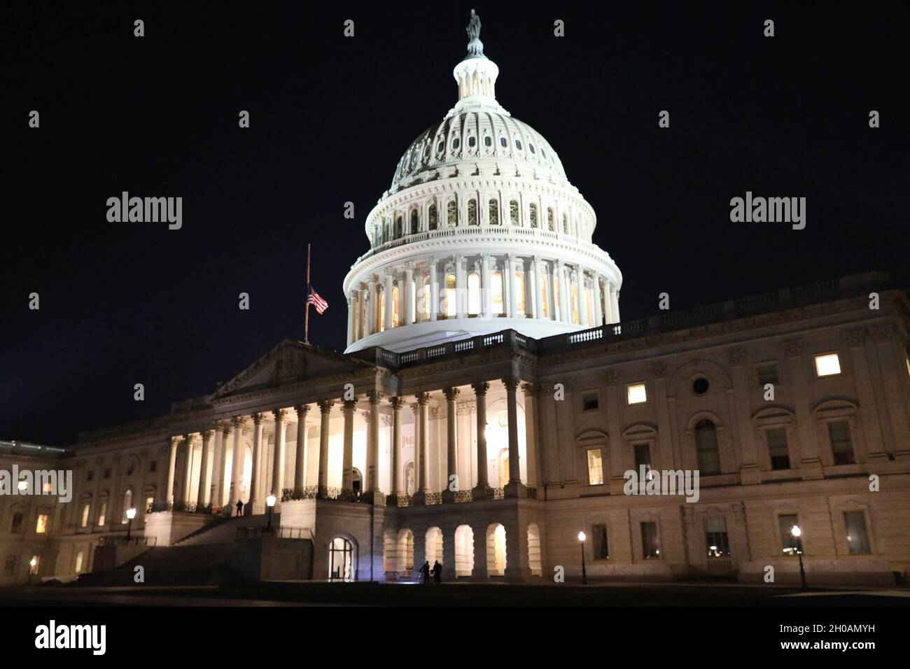 Une photographie de nuit du Capitole des États-Unis à Washington D.C., le drapeau des États-Unis vole à mi-personnel, en l'honneur du bureau de police du Capitole tombé Brian Sicknick, le 12 janvier 2021.Des soldats de la Garde nationale et des aviateurs de plusieurs États se sont rendus à Washington pour apporter leur soutien aux autorités fédérales et de district jusqu'à la 59ème inauguration présidentielle. Banque D'Images