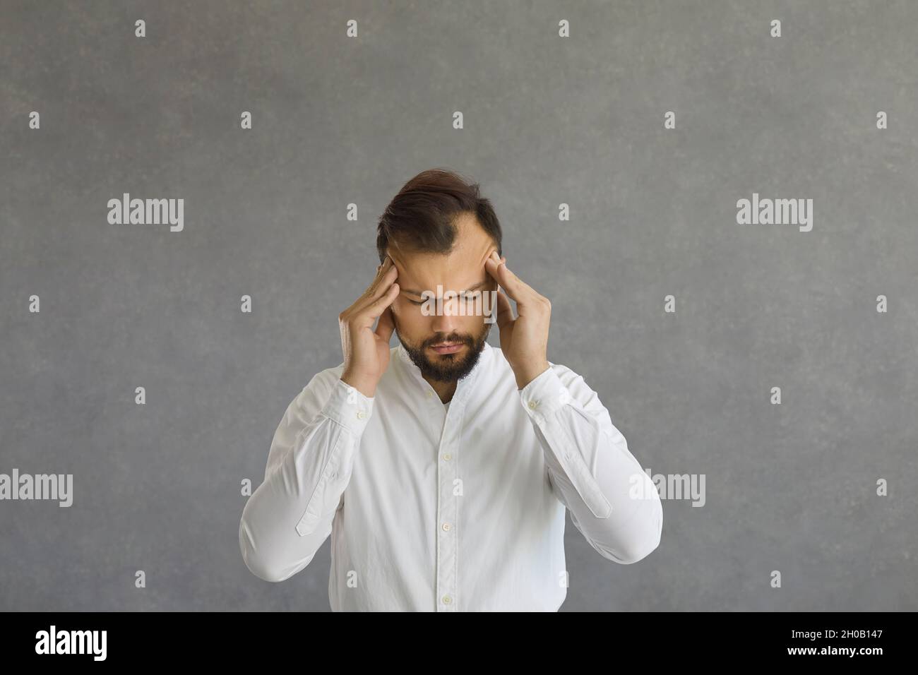 Jeune homme fatigué stressé faisant un massage de la tête essayant de se calmer et de soulager la douleur Banque D'Images
