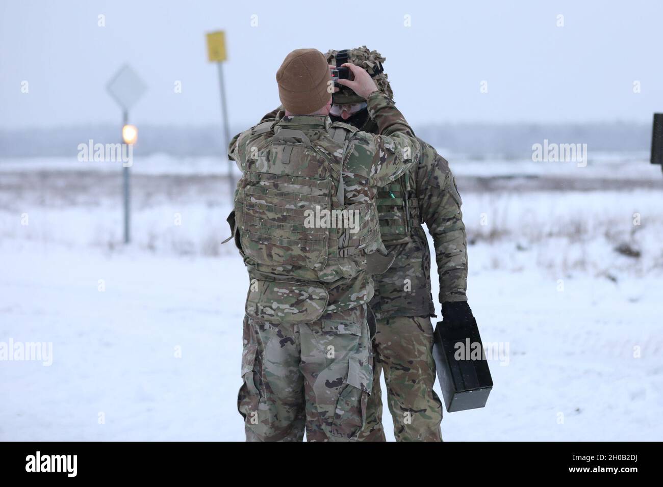 UK Cassino Trooper de la présence avancée renforcée Battle Group Pologne aide son budy de bataille à ajuster son casque lors d'un cours opérateur d'armes à plate-forme sur une aire couverte de neige le 14 janvier 2021, à la zone d'entraînement de Bemowo Piskie. Banque D'Images