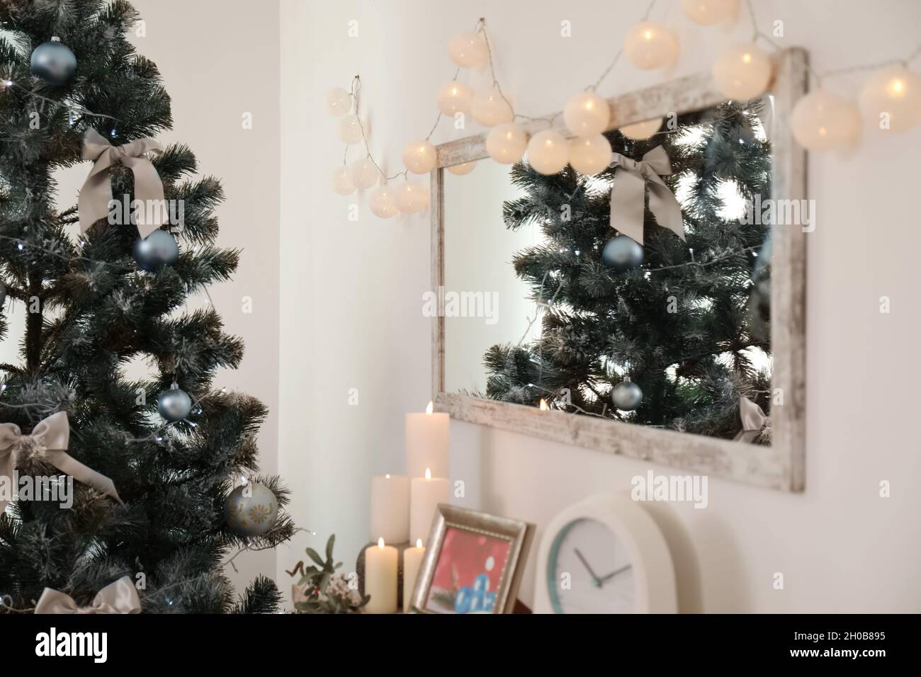 Miroir avec lumières de Noël sur le mur et sapin décoré dans l'intérieur  élégant du salon Photo Stock - Alamy