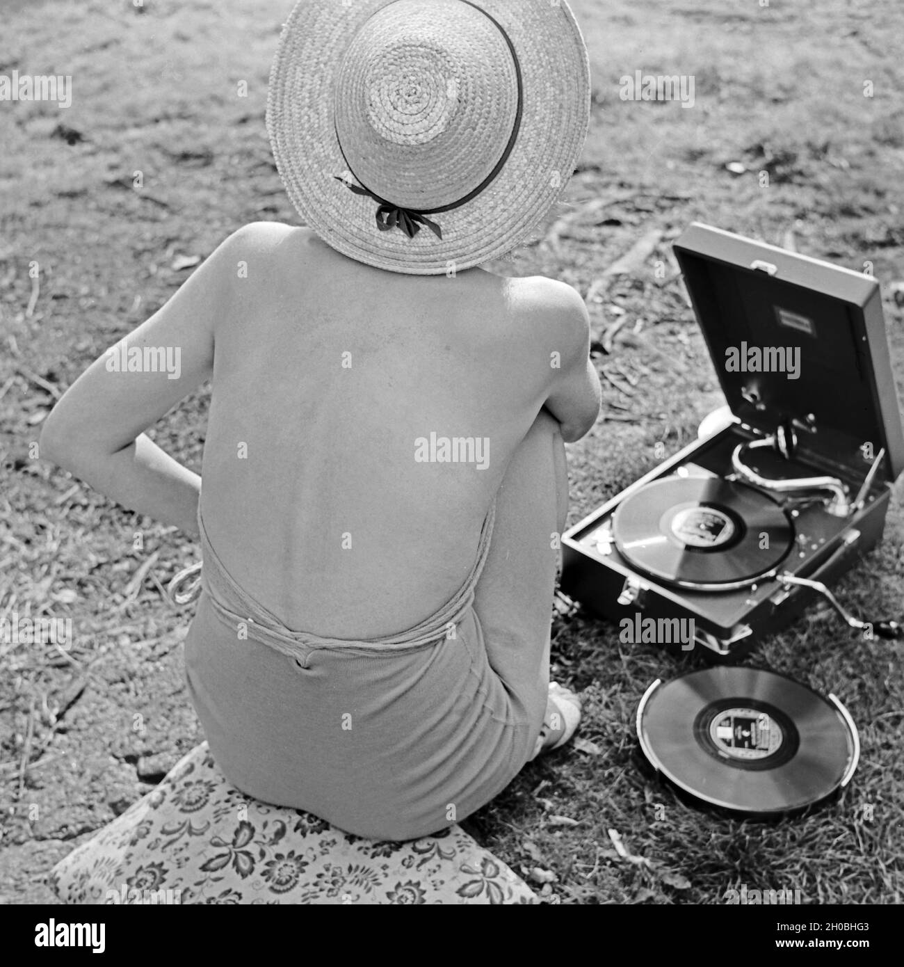 Rückansicht einer Frau im Badeanzug, die sich die neuesten Schlager auf ihrem Koffergrammophon anhört, 1930er Jahre Deutschland. Vue arrière d'une femme en maillot de bain, à l'écoute des derniers hits à partir de leur portable gramophone, Allemagne 1930. Banque D'Images