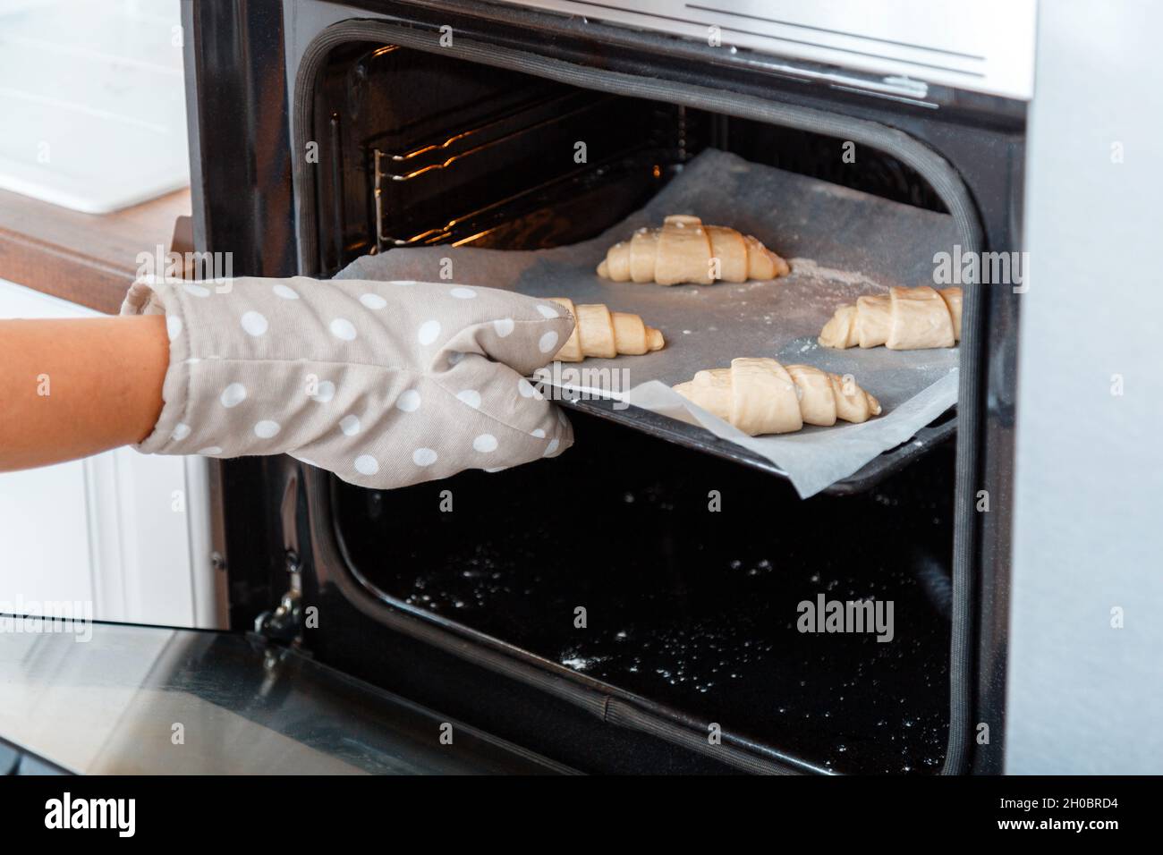 Mini croissants français traditionnels crus non cuits sur plaque de cuisson  pour cuire au four.Petit déjeuner concept de boulangerie française.Main  femelle dans le gant Photo Stock - Alamy
