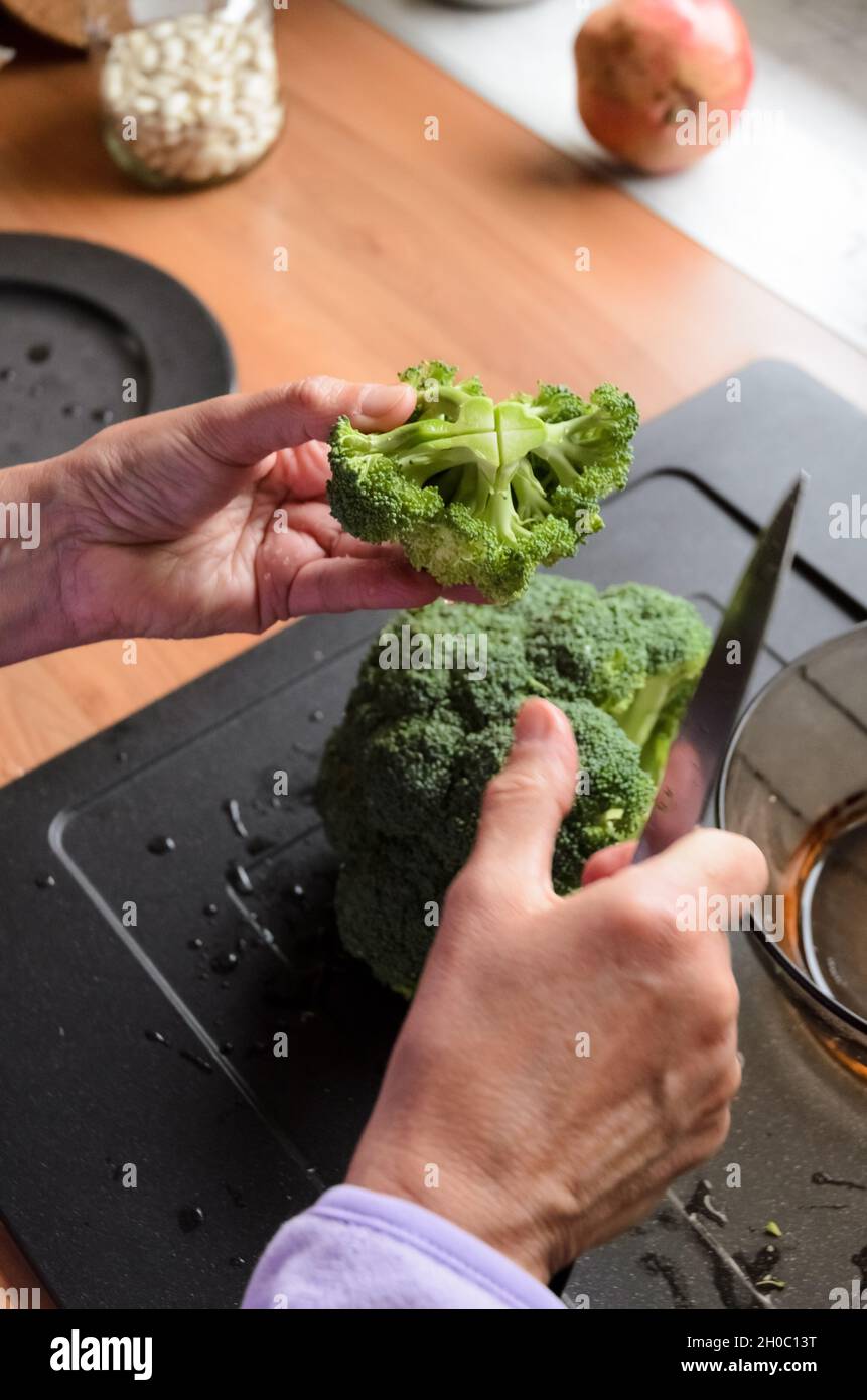 Préparer et trancher des brocolis verts (Brassica oleracea) à la main pour le déjeuner dans la cuisine, vue d'en haut Banque D'Images