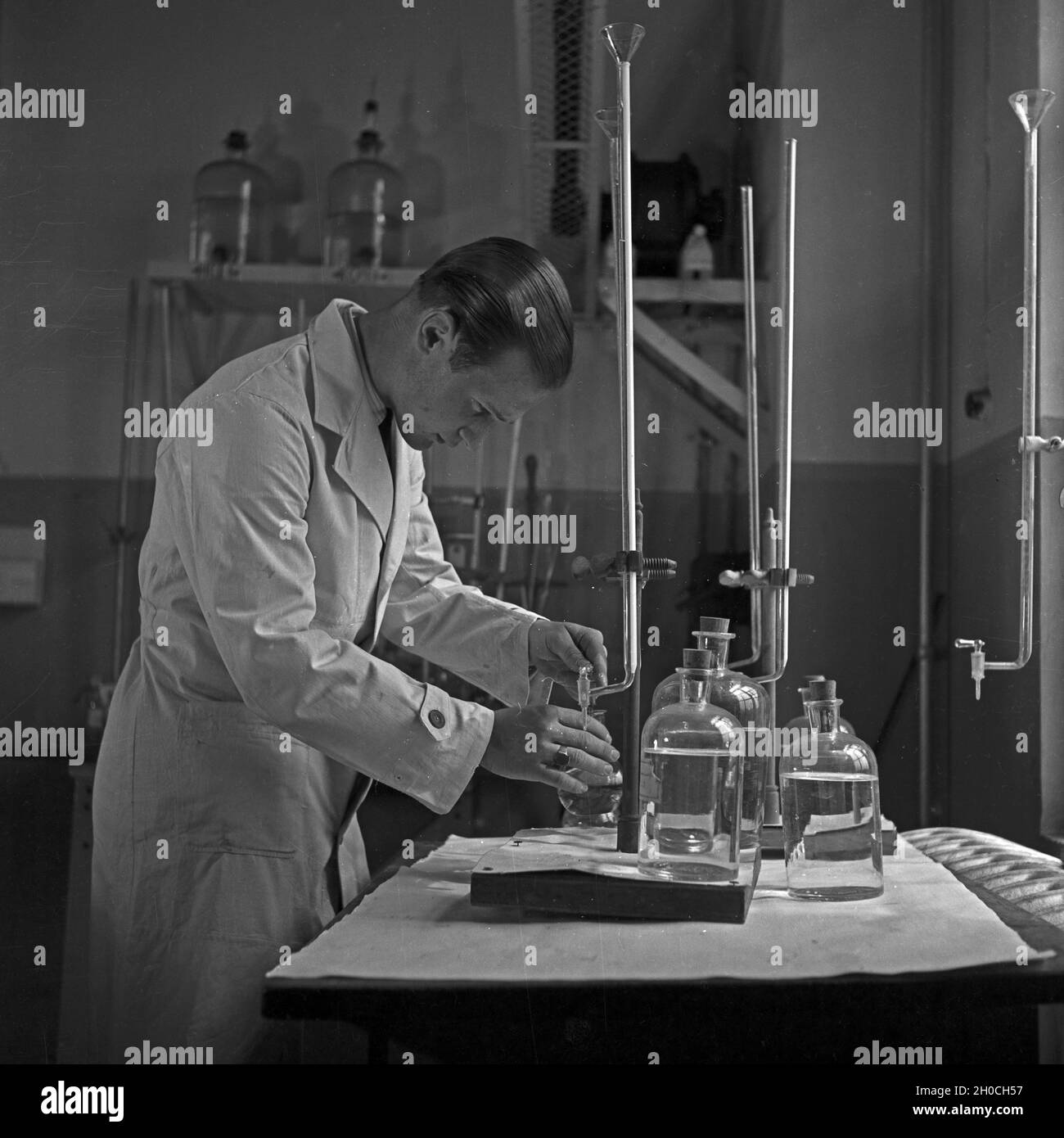 Ein wissenschaftlicher Mitarbeiter prüft Cheimkalien im Labour, Deutschland 1930er Jahre.Un membre du personnel scientifique qui vérifie les produits chimiques au laboratoire, Allemagne des années 1930. Banque D'Images