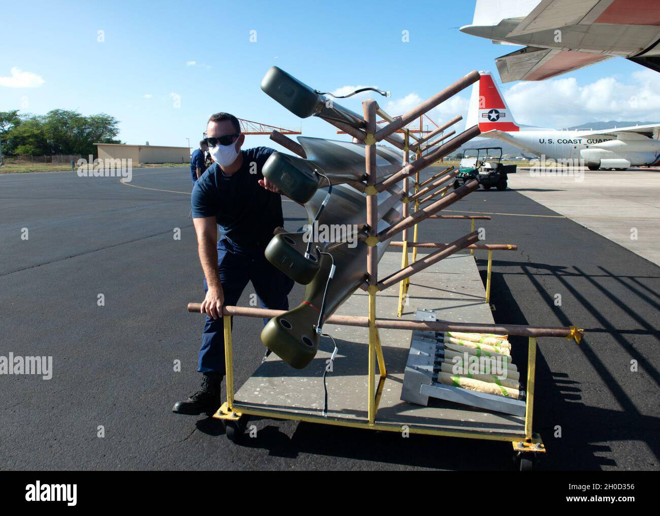 Un équipage de Barbers point de la station aérienne de la Garde côtière décharge les pales de rotor d'un hélicoptère MH-65E Dolphin d'un avion HC-130 Hercules à Oahu, Hawaï, le 28 janvier 2021.Le modèle Dolphin 'echo' remplace les anciens modèles 'delta' de la Garde côtière. Banque D'Images