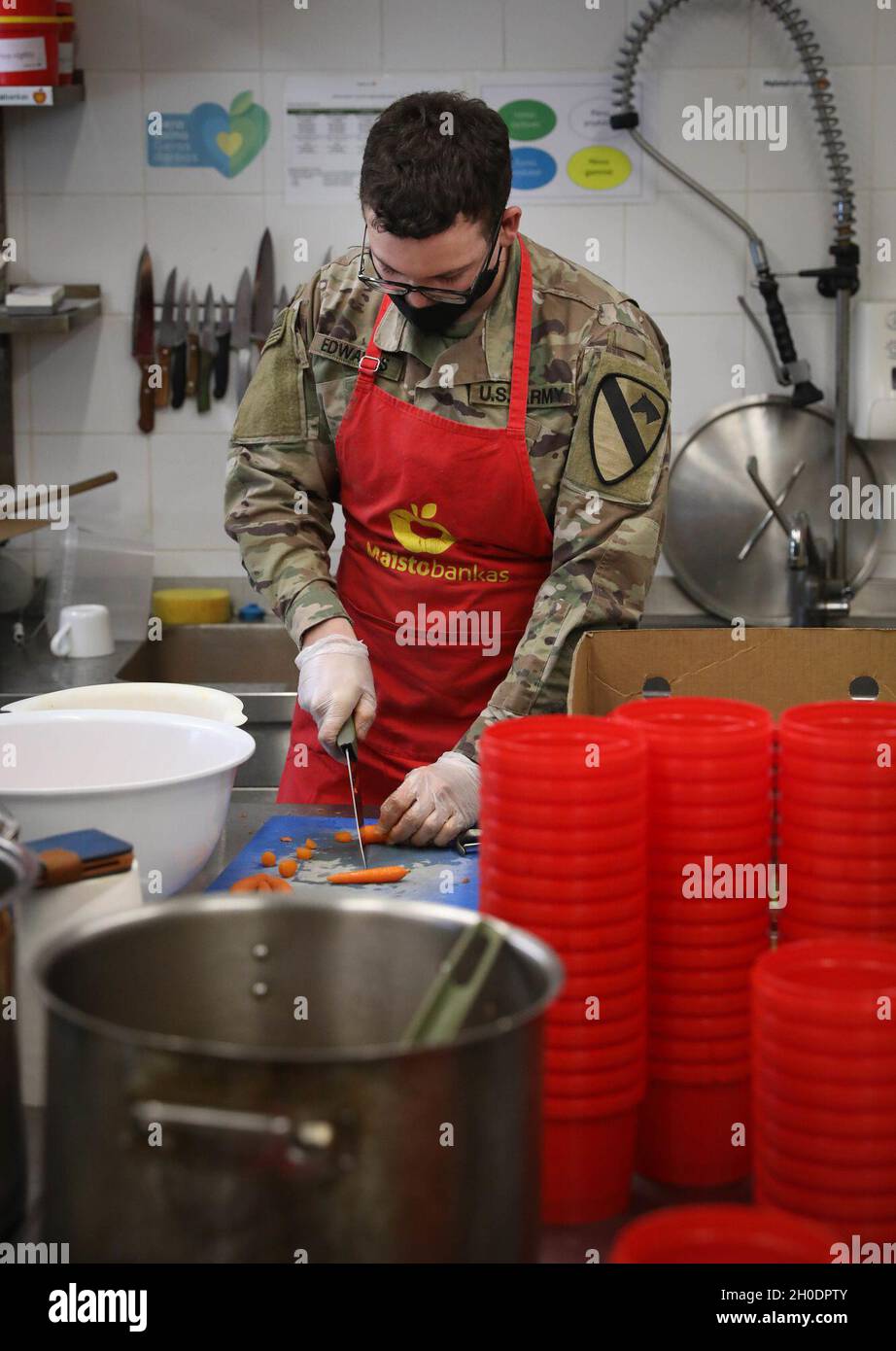 SPC.Austin Edwards, un cavalier affecté au 2e Bataillon, 8e Régiment de cavalerie, coupe des carottes pour ajouter à la soupe le 4 février 2021, dans une banque alimentaire de la ville du capitole de Vilnius, Lituanie.Edwards a contribué à transformer des fruits et des légumes qui ne pouvaient pas être vendus dans les épiceries locales, de la « nourriture laides » à une soupe qui a été distribuée à la population locale sans abri.Il a offert environ cinq heures de sa journée pour aider deux employés de cuisine qui font environ 650 repas par semaine. Banque D'Images