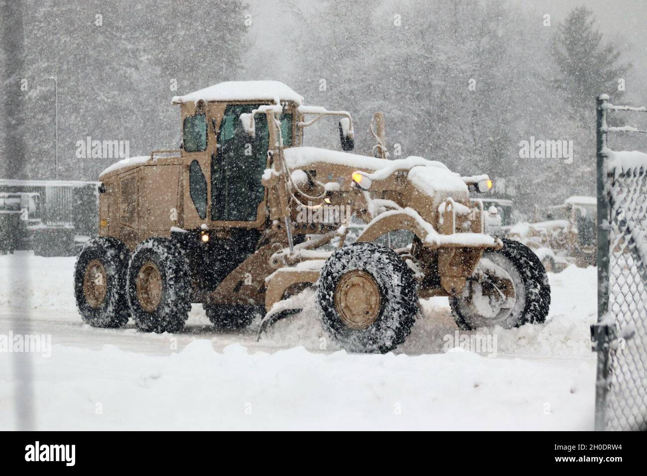 Un membre du personnel du site régional d’entraînement – entretien conduit un niveleur pour déplacer la neige à mesure que la neige abondante tombe le 4 février 2021, à fort McCoy, dans le Wisconsin. RTS – entretien forme des centaines de soldats chaque année dans le MOS de la série 91 de l’Armée de terre et soutient administrativement l’entraînement des soldats dans le MOS 89B.L'unité s'aligne sous la 3e Brigade (Ordnance), la 94e Division du 80e Commandement de l'entraînement, et est située au centre de la zone du cantonnement avec un complexe entier pour l'entraînement. Banque D'Images