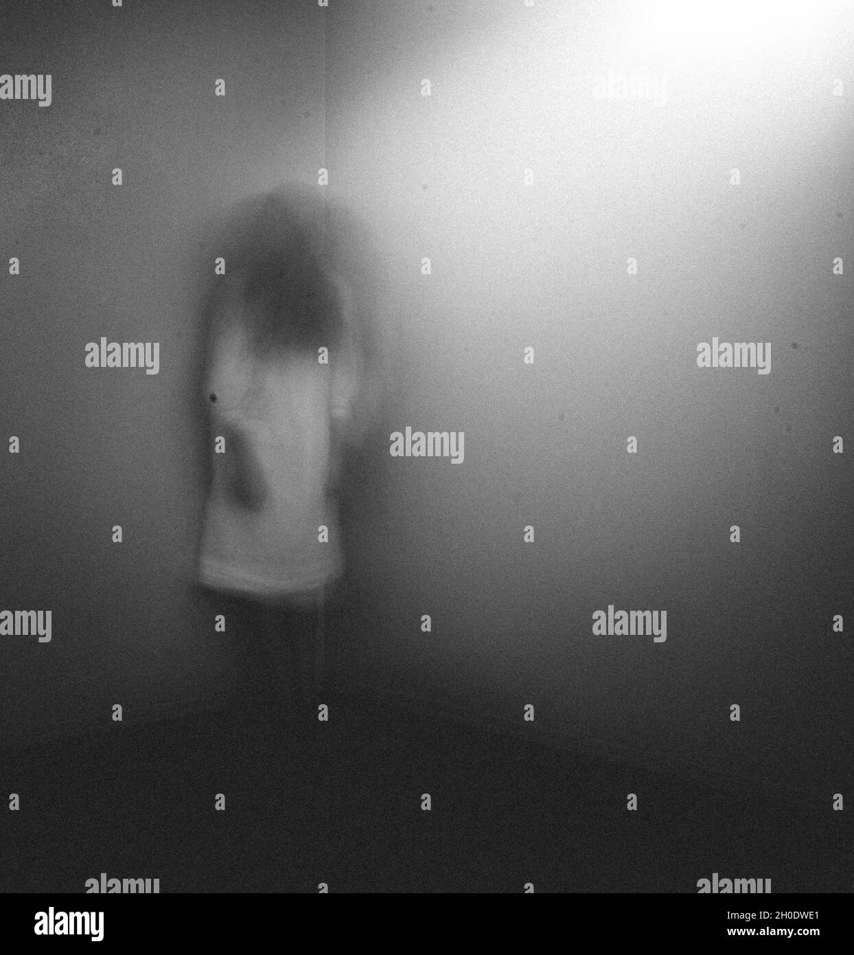Fille fantôme dans la chemise de nuit blanche debout dans le coin de la chambre à la maison Banque D'Images