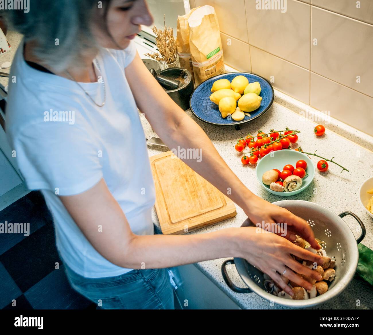 Une femme met des légumes dans une passoire tout en cuisant le dîner Banque D'Images