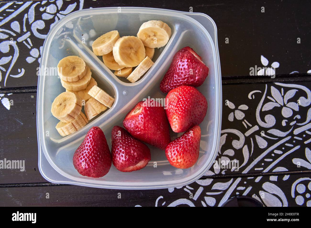 en-cas de fruits sains pour les enfants à emporter à l'école.Banane et fraise dans un bol sur une table en bois peinte en noir.Horizontale Banque D'Images