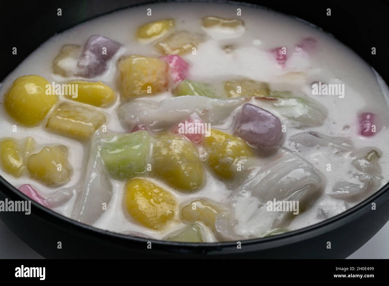Vue rapprochée de délicieux desserts thaïlandais faits maison boules de riz collantes avec du ginkgo et de la viande de noix de coco dans le lait de coco dans un bol noir. Banque D'Images