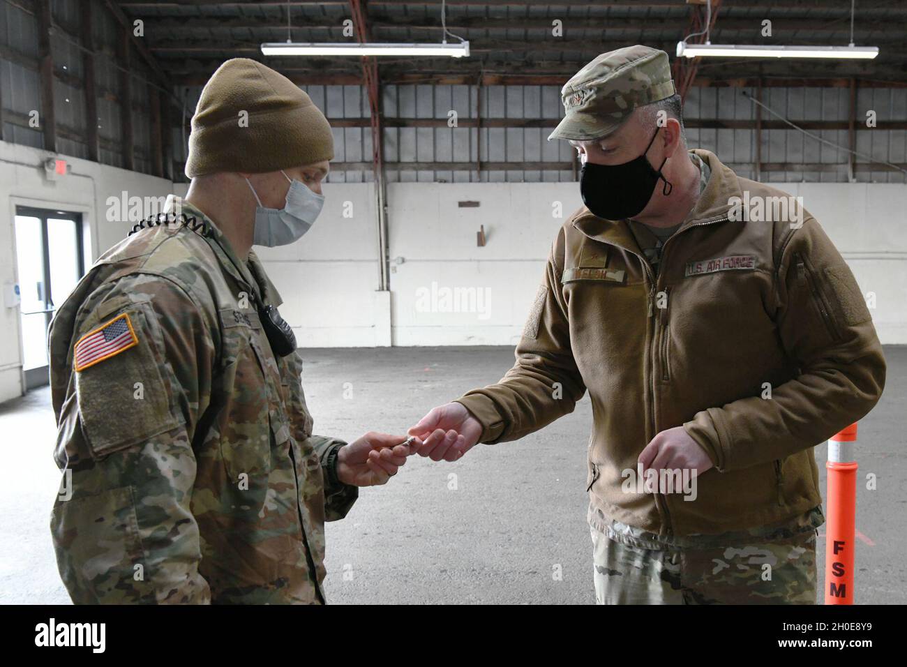 Bang.Le général Gent Welsh, Washington le commandant de la Garde nationale aérienne (à droite) présente sa pièce de commandant à la Garde nationale de l’Armée de terre le 2e lieutenant David Stevens (à gauche) affecté au 303e Régiment de cavalerie au site de vaccination de masse des champs de foire du comté de Clark à Ridgefield, Washington, le 9 février 2021.Le champ de foire du comté de Clark est l'un des quatre sites de vaccination de masse que le département de la Santé de l'État de Washington a lancé autour de l'État et est soutenu par des membres de l'armée de Washington et de la Garde nationale aérienne.( Banque D'Images