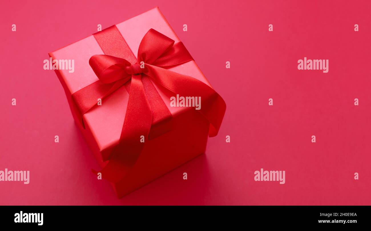 Boîte cadeau de Noël rouge noeud avec ruban sur fond rouge, surprise de la Saint-Valentin, cadeau de vacances du nouvel an, décoration en satin.Espace de copie, Banque D'Images
