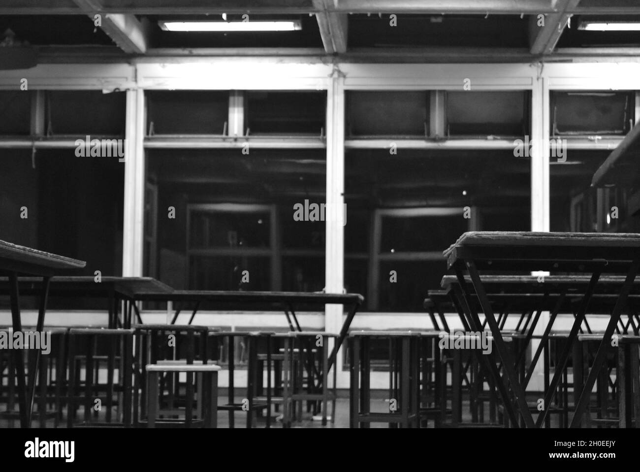 Salle de classe sombre vide avec des bureaux en bois en noir et blanc Banque D'Images