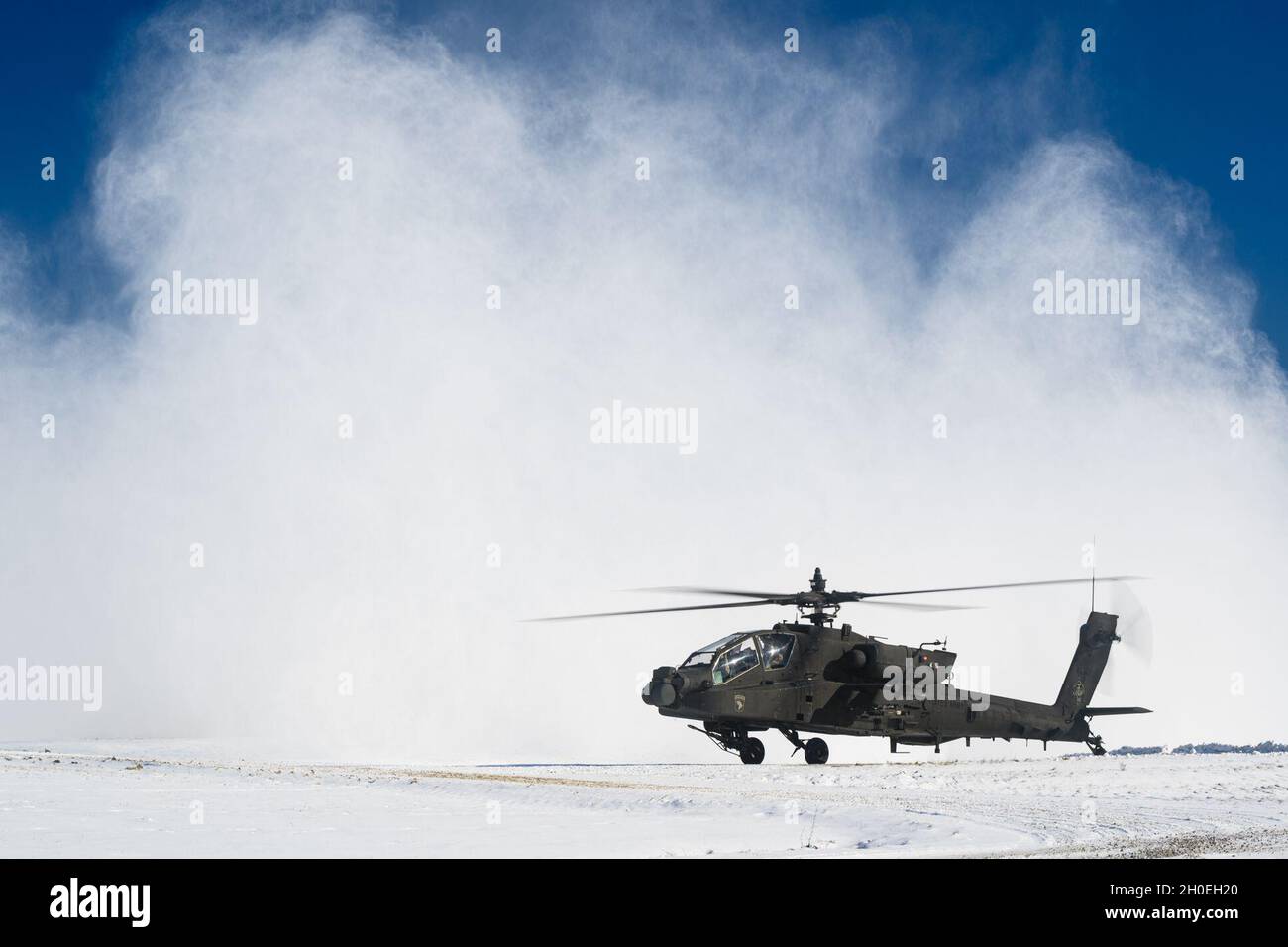 Un Apache AH-64 de l'armée américaine, appartenant au 1er Bataillon de l'Alpha Company, 101e Brigade de l'aviation de combat, est assis devant un panache de neige après son arrivée à la zone d'entraînement Hohenfels pour la résolution combinée XV, le 12 février 2021. Banque D'Images