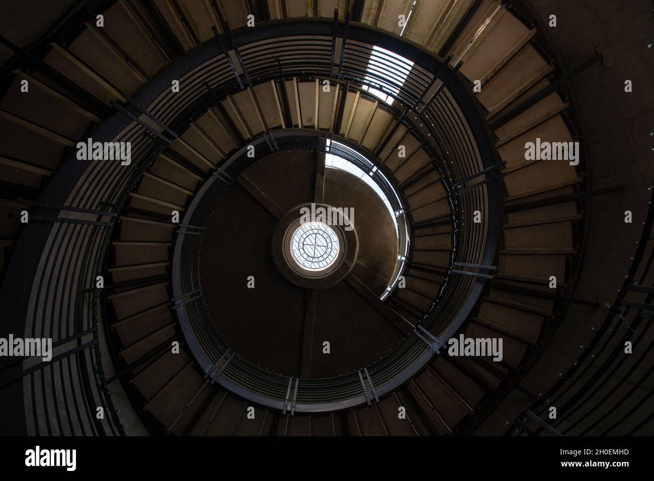 Les escaliers à l'intérieur d'un silo s'spiralent jusqu'à une fenêtre en haut, créant des lignes dans une conception abstraite. Banque D'Images
