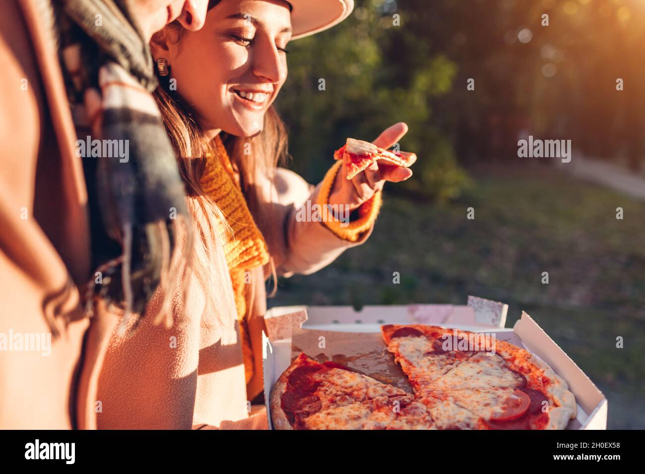 Couple aimant ayant la pizza pepperoni dans le parc d'automne.Femme et homme apprécient la nourriture savoureuse à l'extérieur.En-cas chauds Banque D'Images