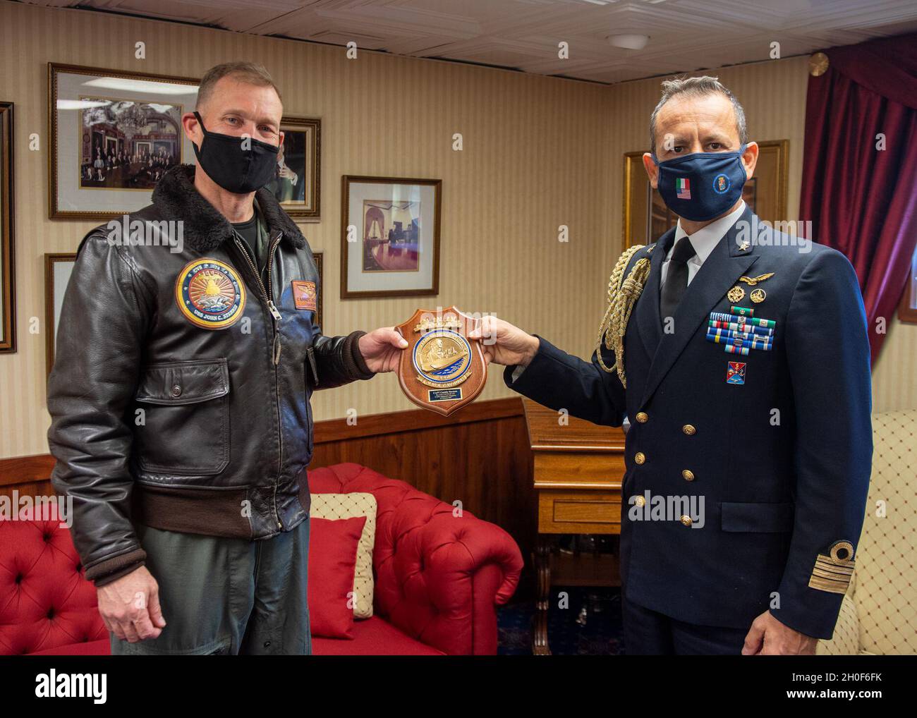 Le capitaine de la Marine italienne Gianfranco Vizzini, attaché naval de droite, présente un cadeau au nom du capitaine de la Marine italienne Giancarlo Ciappina, commandant du porte-avions ITS Cavour (CVH 550), au capitaine de la Marine américaine Cassidy Norman, commandant du porte-avions USS John C. Stennis (CVN 74),Dans le cadre d’un échange de cadeaux dans la cabine portuaire du capitaine à bord du John C. Stennis, à Norfolk, en Virginie, le 22 février 2021.Le John C. Stennis collabore avec Newport News Shipbuilding pour effectuer la révision du complexe de ravitaillement selon les délais, avec un équipage formé, résilient et cohésif. Banque D'Images