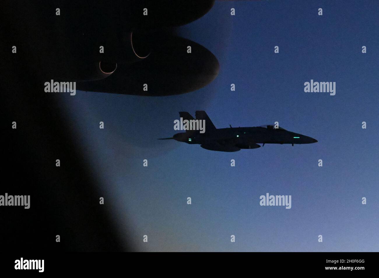 F/A-18 un chasseur Hornet survole à côté d'un HC-130J combat King II en préparation pour le ravitaillement aérien nocturne à grande vitesse le 22 février 2021.L'achèvement de cette étape appuie l'interopérabilité des services communs et améliore le succès des opérations militaires dans le monde entier.Cette capacité du HC-130J augmente les actifs disponibles pour mener des opérations conjointes là où d'autres aéronefs ne sont pas disponibles, ce qui permet à la mission de continuer sans entrave. Banque D'Images