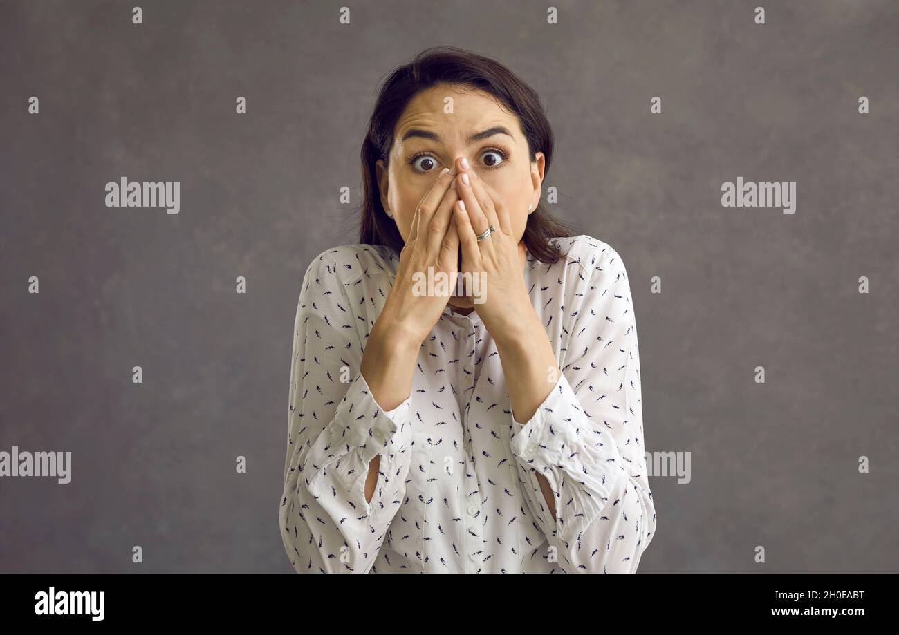 Jeune femme effrayée couvrant la bouche avec la main regardant la prise de vue en studio Banque D'Images
