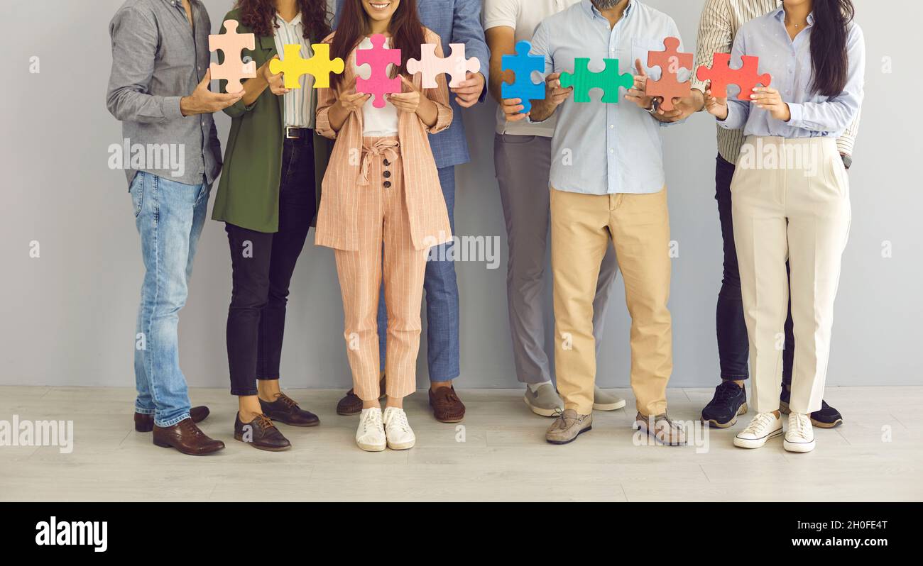 Une équipe de professionnels créatifs se tenant ensemble et joignant des pièces de puzzle Banque D'Images