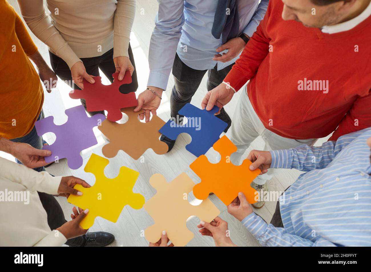 Une équipe d'hommes et de femmes d'affaires se joint à des pièces de puzzle colorées pour montrer le concept du travail d'équipe Banque D'Images