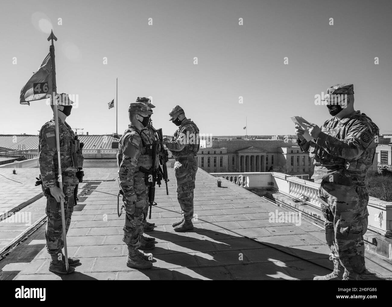 Armée des États-Unis 1er Sgt.Matthew Florida, à droite, lit les ordres de promotion comme le capitaine Dan Ramos, 46e compagnie de police militaire, Michigan National Guard, place le nouveau rang sur les trois soldats au-dessus du bâtiment du Capitole des États-Unis à Washington, D.C., le 25 février 2021.La Garde nationale a été priée de continuer à soutenir les organismes fédéraux d'application de la loi en offrant un soutien en matière de sécurité, de communications, d'évacuation médicale, de logistique et de sécurité aux organismes d'État, de district et fédéraux jusqu'à la mi-mars. Banque D'Images