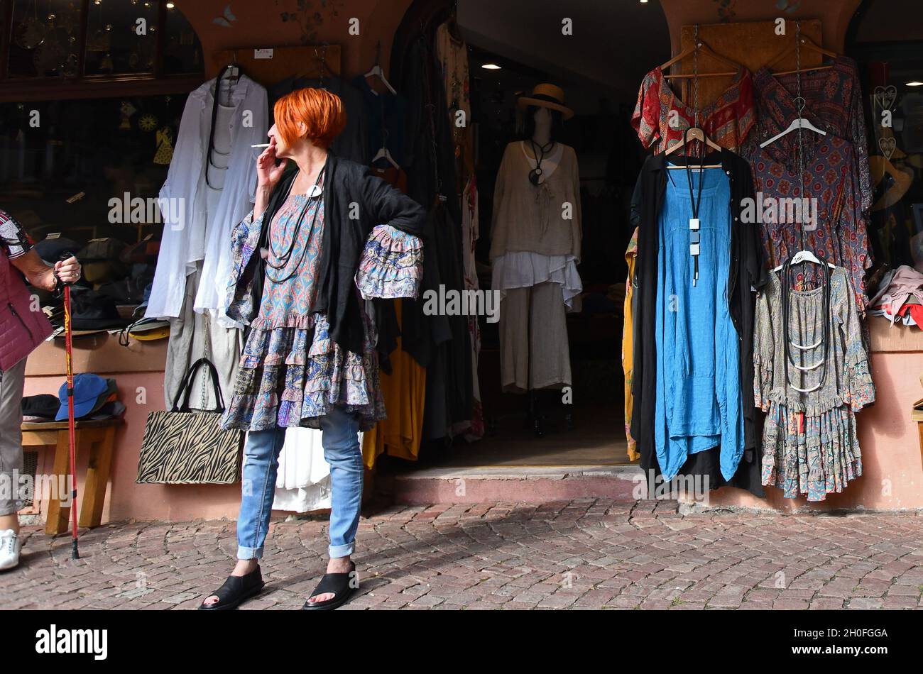 Femme fumant la cigarette à l'extérieur de la boutique de vêtements de mode Banque D'Images
