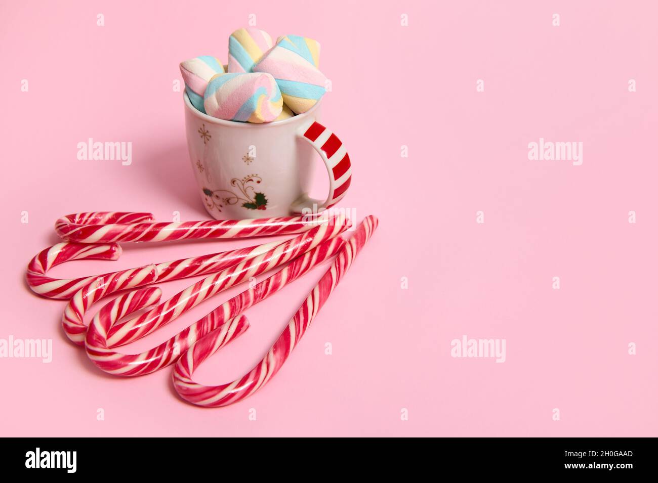 Belle composition de Noël minimaliste avec boisson chaude au chocolat décorée de guimauves et de sucettes rayées, Cannes de bonbons isolées sur la broche Banque D'Images