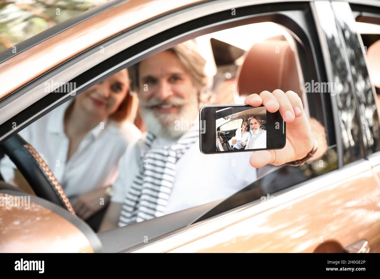 Heureux couple d'âge mûr en voiture sur écran de téléphone mobile Banque D'Images