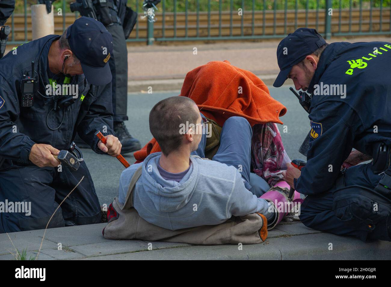 Un activiste est vu d'une main enchâssée dans un tube de ciment et d'une autre supercollée alors que la police tente du libérer lors de la manifestation contre le climat à la Haye.la rébellion contre l'extinction (ER) a organisé une importante manifestation contre le climat à la Haye, qui a impliqué environ 200 à 300 activistes contre le climat.L'ER prévoit d'organiser des manifestations pour les sept prochains jours, certaines annoncées à l'avance et d'autres non, y compris le blocage de l'intersection entre la Chambre temporaire des représentants et le ministère des Affaires économiques et du climat.L'action est une semaine avant une grande conférence des Nations Unies sur le climat, le sommet COP26 à Glasgow, en Écosse Banque D'Images