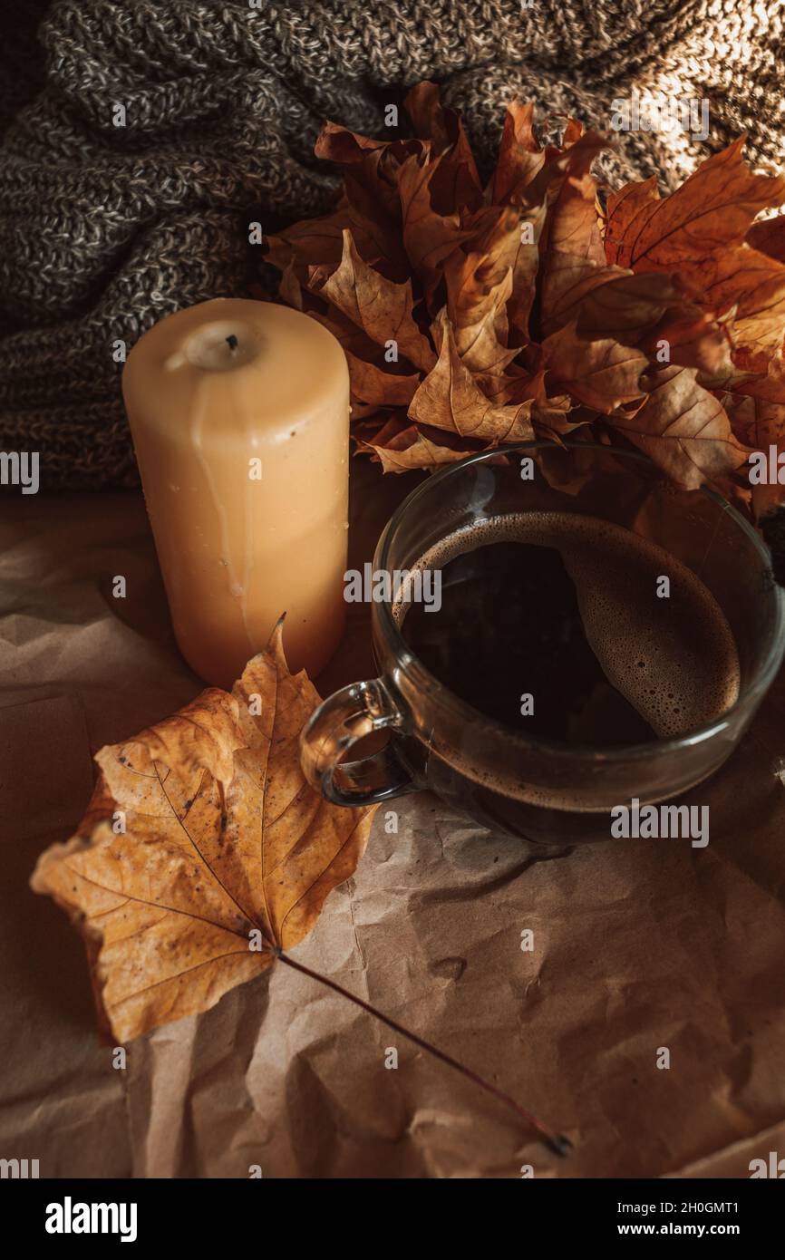 Bougie jaune et grande tasse de café noir dans une maison confortable automne soirée encore vie.Tons orange chaleureux.Tir vertical Banque D'Images