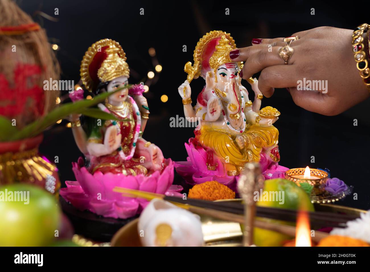 Mains de fille appliquant Roli Tilak sur le front de Ganpati Bappa Morya tout en adorant Maa Lakshmi et Bhagwan Ganesh Deva.Diwali Puja , nouvel an, Deepa Banque D'Images