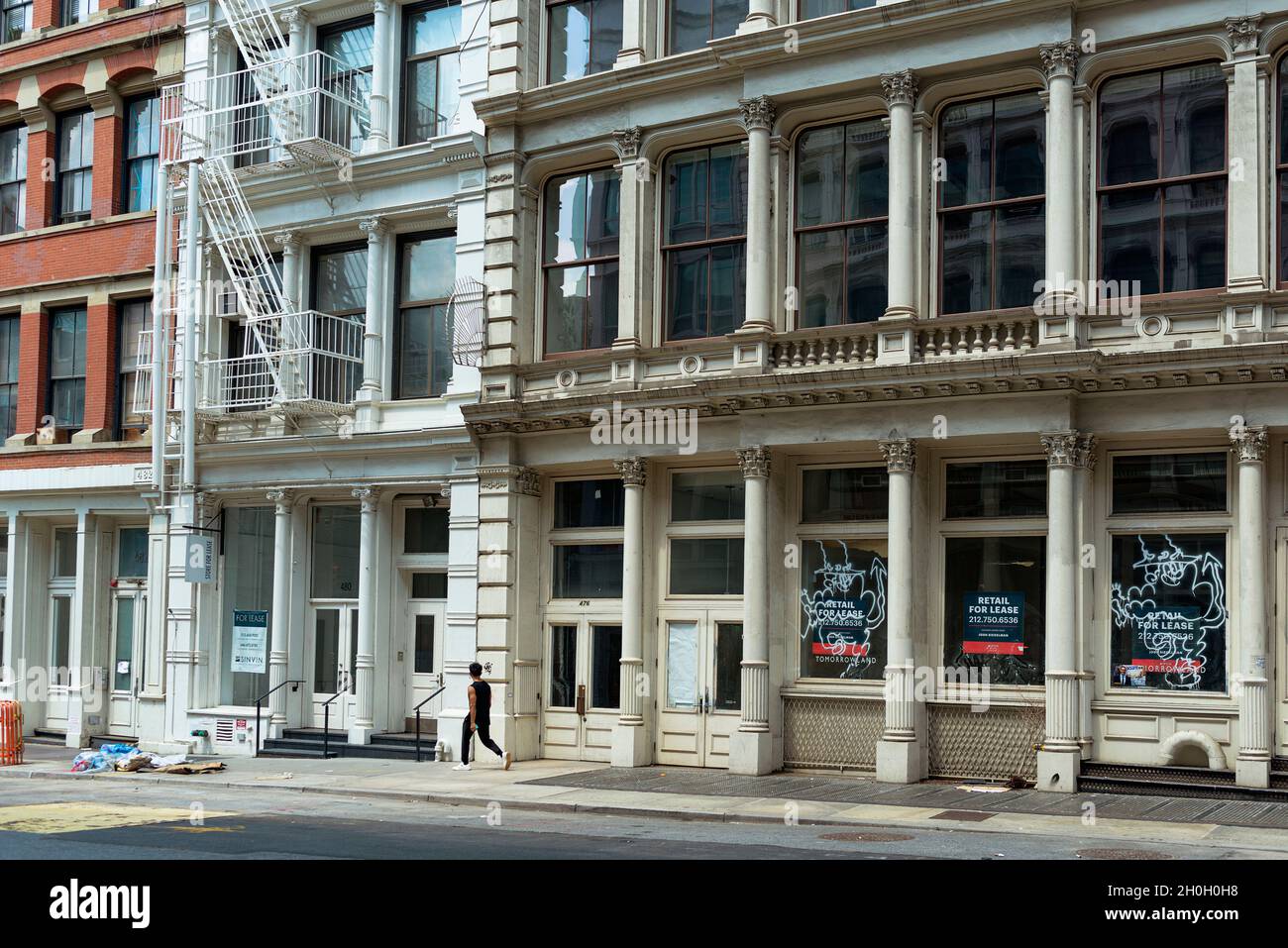 Un homme qui descend Broome Street dans le quartier de SOHO à New York.Les vitrines vides ont des affiches de location. Banque D'Images