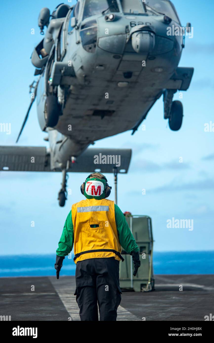 211011-N-DW158-1008 OCÉAN PACIFIQUE (OCT11, 2021) Annabel Archuleta, mécanicien de structures aéronautiques de 3e classe, d’Austin, Texas, dirige un Hawk de mer MH-60S, attaché aux Falcons d’or de l’Escadron de combat en mer (HSC) 12, sur le pont de vol du seul porte-avions déployé par l’avant de la Marine américaine, l’USS Ronald Reagan (CVN 76), au cours d’une reconstitution verticale.Ronald Reagan, le navire amiral du Carrier Strike Group 5, fournit une force prête à combattre qui protège et défend les États-Unis, et soutient les alliances, les partenariats et les intérêts maritimes collectifs dans la région Indo-Pacifique.(U Banque D'Images